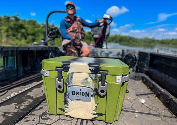 orion cooler on the front deck of a jon boat with smiling motorist behind it